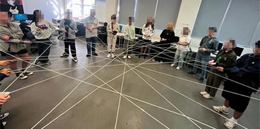AUT Students standing in a circle with string.